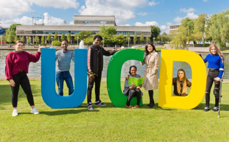 Seven UCD students of different abilities and ethnicities posing by big colourful letters spelling out 'UCD'.